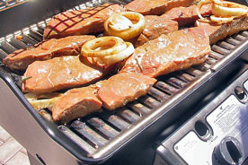 steaks and onion rings on a gas grill