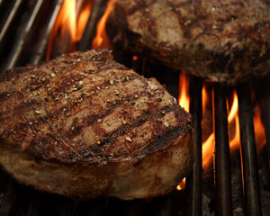 steaks cooking on a barbecue grill